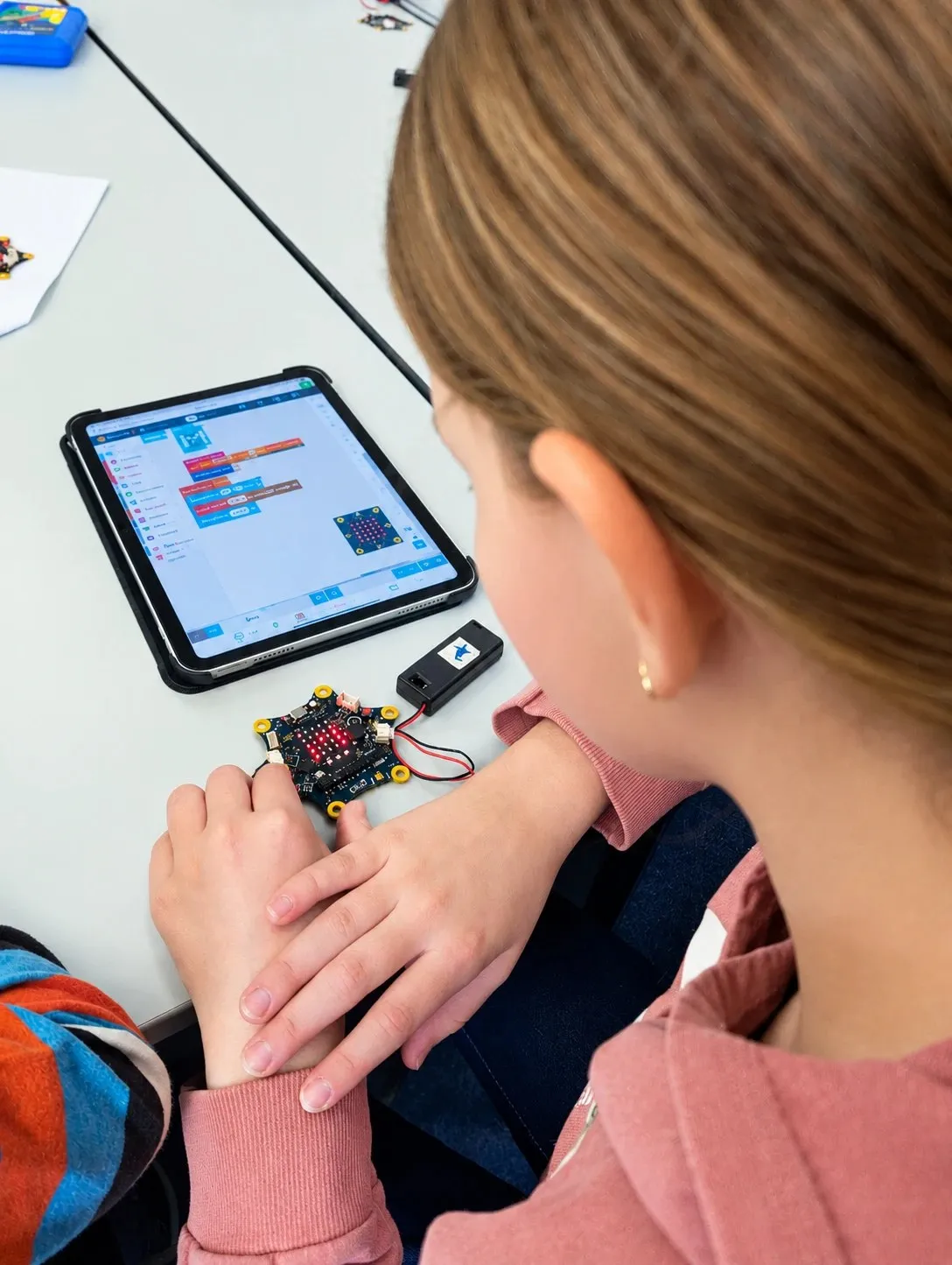 Kind programmiert mit dem Tablet einen Calliope mini
