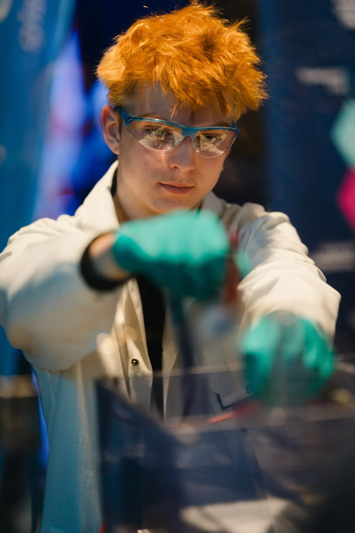 Jugendlicher mit Schutzbrille und Laborkittel beim Experimentieren