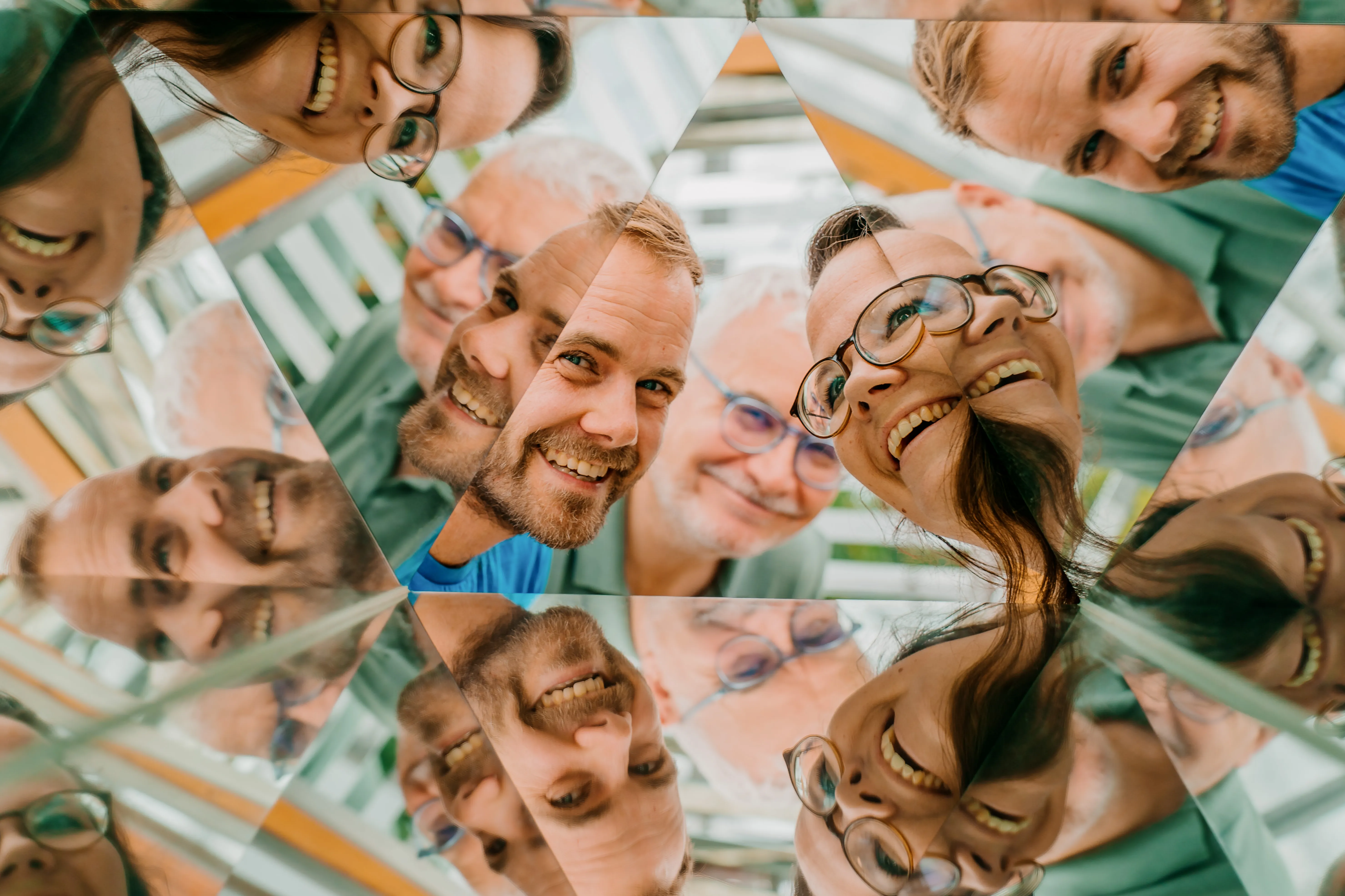 Lachende Gesichter des curiocity-Teams, vervielfacht in einem Kaleidoskop-Spiegel im Pop-up Science Center Freising